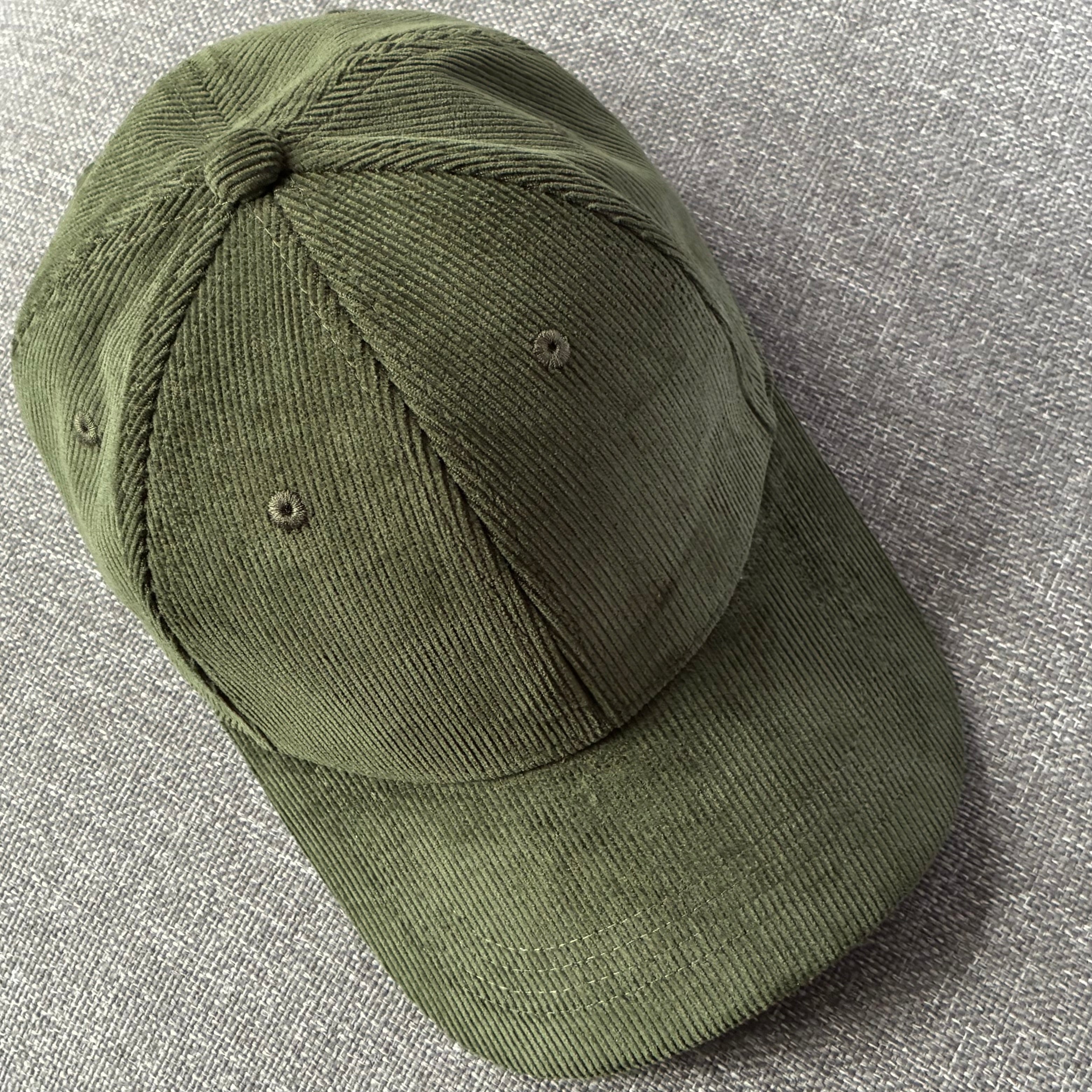 Forest Night green organic cotton corduroy cap on a textured grey surface.
