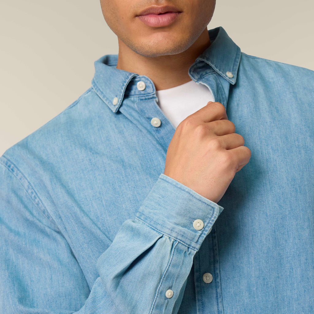 Man wearing a light blue denim shirt against a neutral background