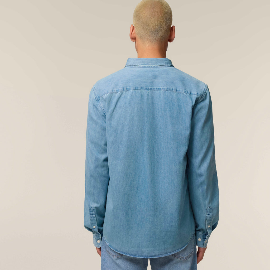 Back view of a man wearing the light wash blue men's denim shirt against a neutral background