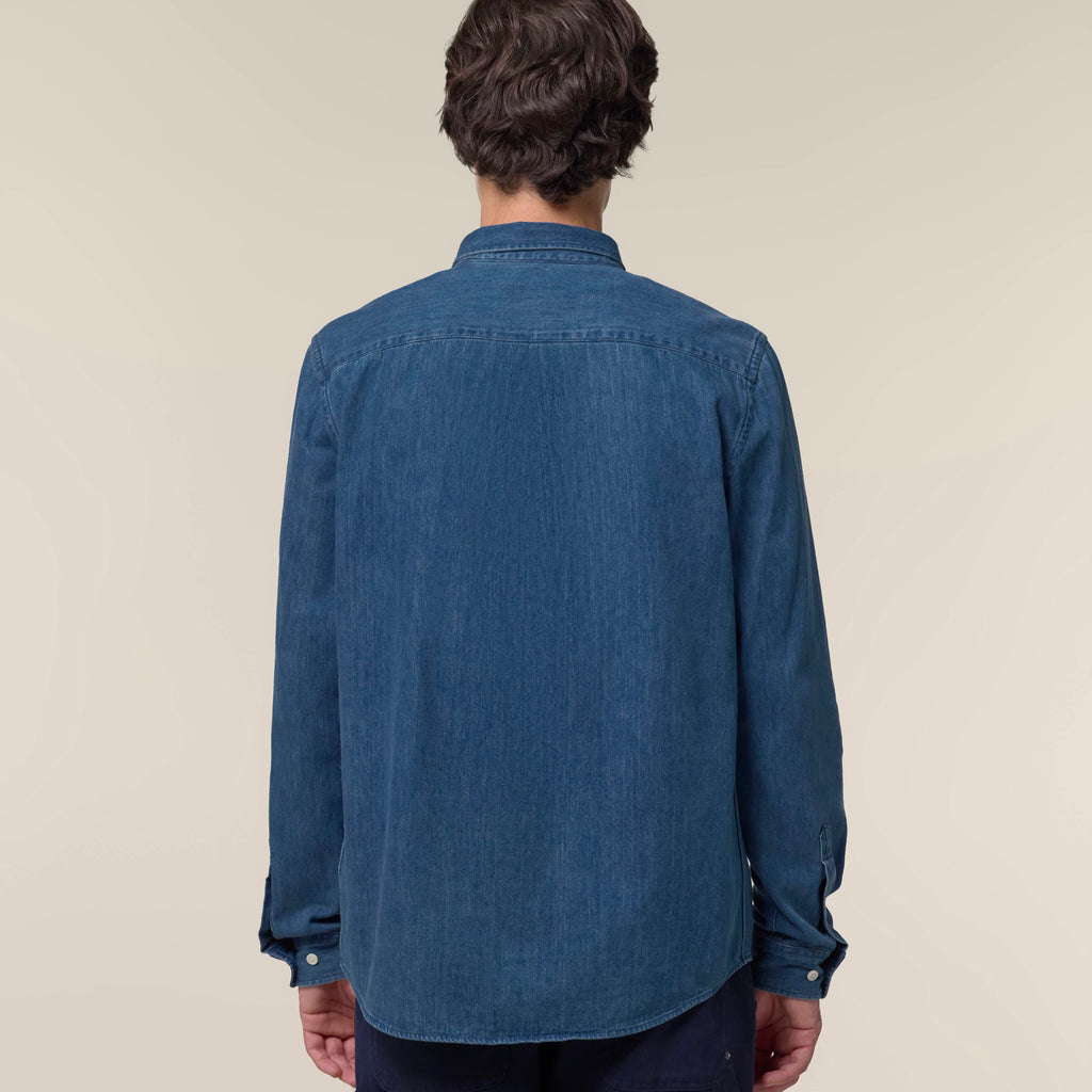 Back view of a man wearing the mid wash blue men's denim shirt against a neutral background
