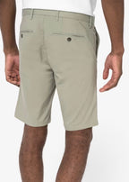 A man shown from the back, from the waist down wearing almond green coloured chino shorts, against a neutral background.