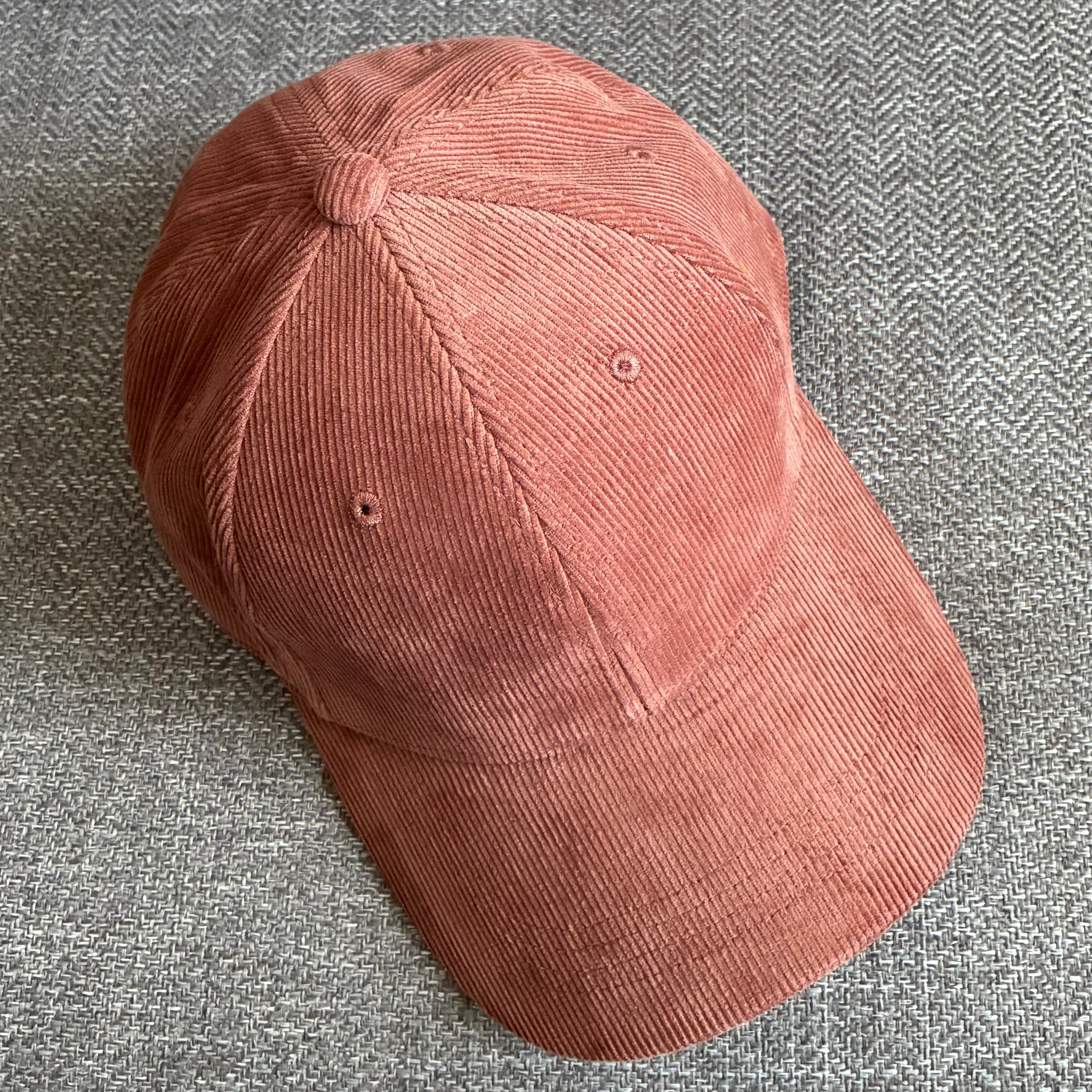 Redwood organic cotton corduroy cap on a textured grey fabric surface.