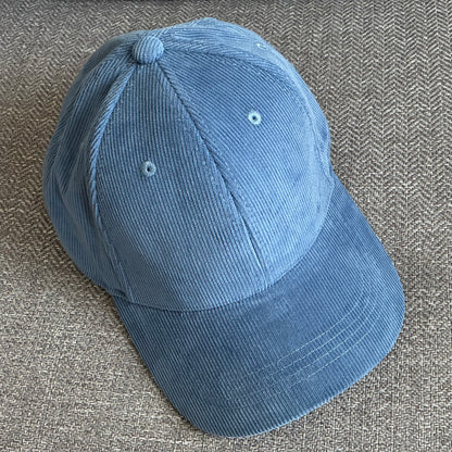 Slate Blue organic cotton corduroy cap on a textured grey surface.
