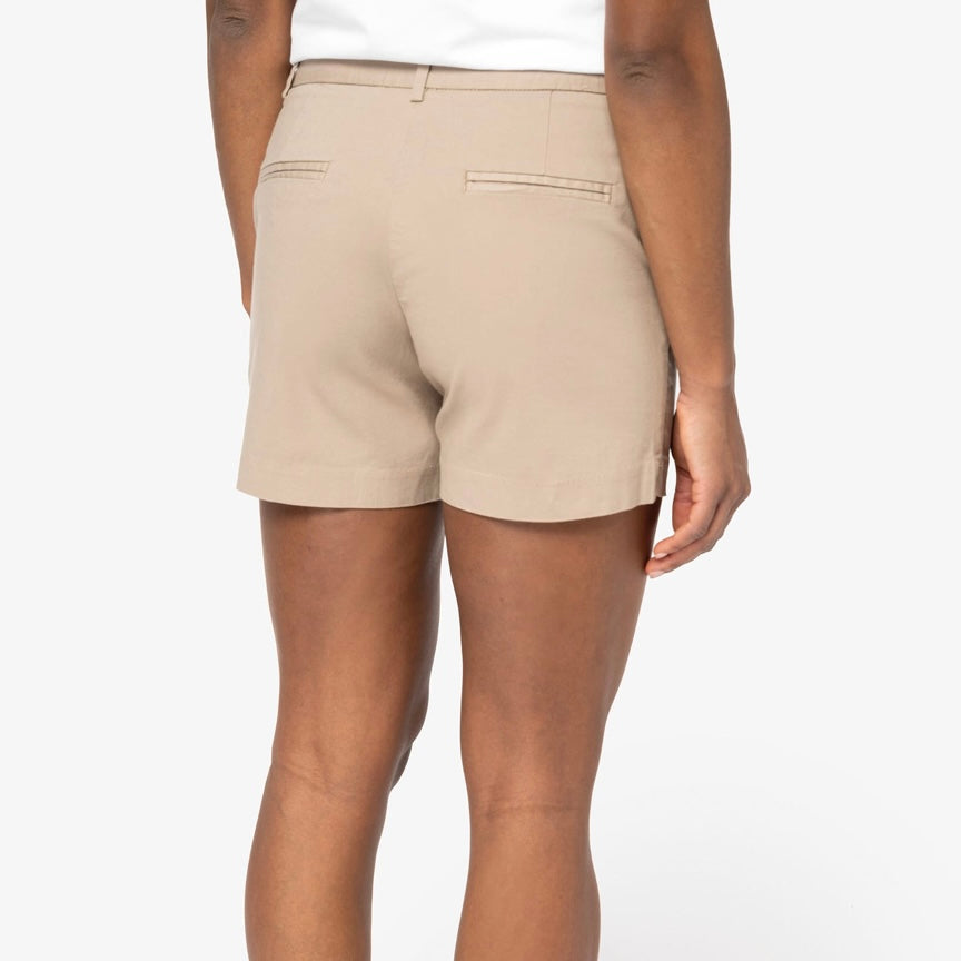 A woman shown from the back wearing sand dune coloured chino shorts with two welt back pockets, photographed against a neutral studio background.